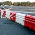 Line of red and white RB22 heavy duty water filled crash barriers