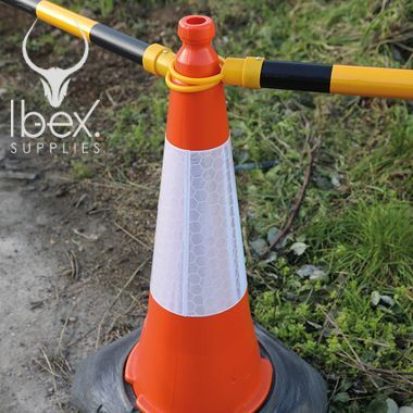 Black and yellow telescopic demarcation poles linked around orange and white cones